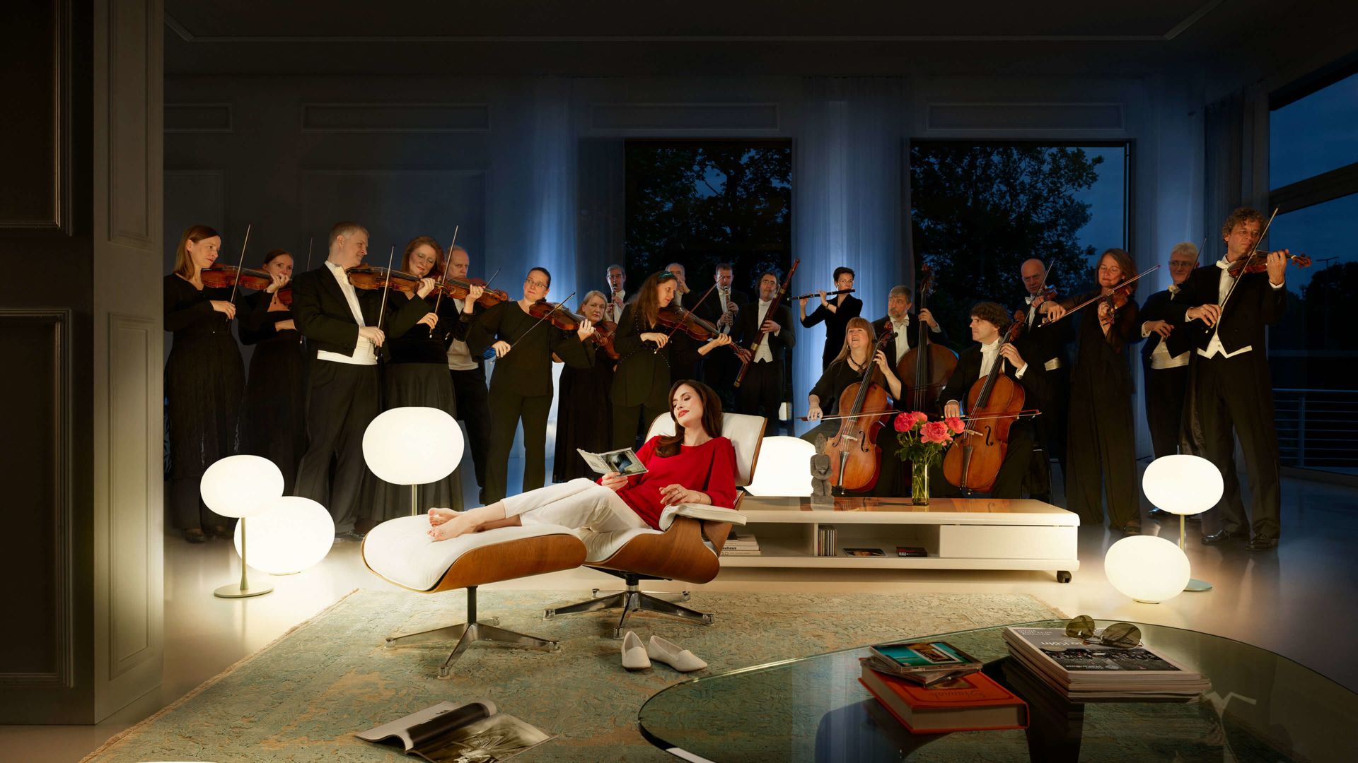 Lady sits relaxed in her armchair and listens to her music quite enraptured, as if the orchestra was in her living room.